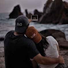 a man and woman are sitting on the beach taking pictures with their cell phones,