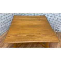 a wooden table sitting on top of a hard wood floor next to a brick wall