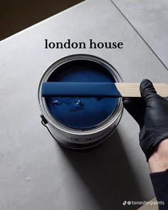 a person is holding a paintbrush over a blue bucket with the words london house painted on it