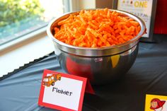 a bowl full of cheetos sitting on top of a table next to a sign