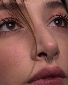 a close up of a woman's nose with piercings on her nose ring