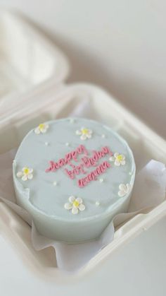 a white cake with pink frosting and flowers on it in a plastic container that says happy birthday victoria