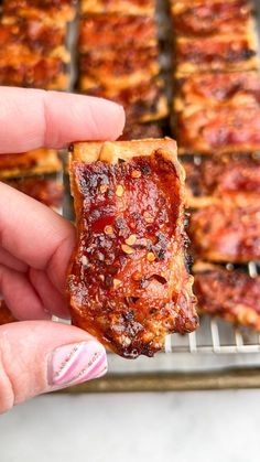 a person holding up a piece of pizza on a rack with other food items in the background