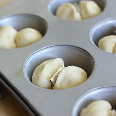 a muffin tin filled with doughnuts on top of a wooden table