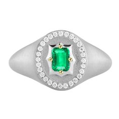 an emerald and diamond ring on a white background