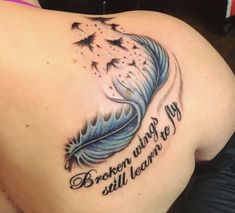 the back of a woman's shoulder with a blue feather and words on it