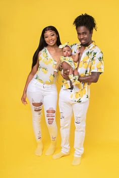 a man and woman holding a baby in front of a yellow background wearing matching outfits