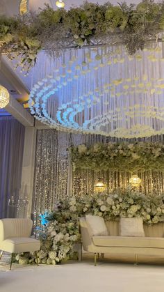 an elegant wedding setup with chandeliers and flowers on the wall, couches and chairs