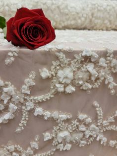 a red rose sitting on top of a table next to some white lace and flowers