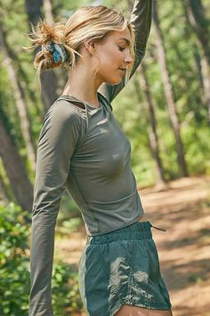 a woman holding a frisbee in her hand while standing on a dirt road