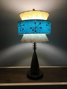 a lamp with a blue and white shade on it sitting on top of a wooden table