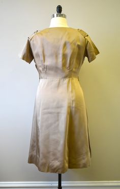 "Description: 1950s taupe satin wiggle dress. It has a draped, pleated portrait V-neckline with rosette details, and there is a swag and rosette detail on the front of the skirt. It has short sleeves, and it is unlined. It has a side metal zipper closure. Condition: In fair to good condition. It has a few tiny scattered spots, and tiny holes. It is missing its belt. Designer: Fashioned by Form Fit Stated Size: n/a Measurements: Armpit to armpit: 22\" Sleeve length (neck to cuff): 11\" Waist: 34\ Fitted Silk Vintage Dress For Vintage Fashion, Fitted Vintage Satin Dress, Fitted Retro Satin Dresses, Vintage Satin Dress For Vintage Events, Fitted Silk Vintage Dress, Fitted Silk Dress For Vintage Events, Fitted Bias Cut Dresses For Vintage Fashion, Retro Fitted Satin Dress, Silk Beige Dress For Vintage Events