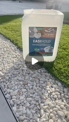 a gallon of water sitting on top of a grass covered ground next to a sidewalk