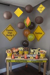 a table topped with lots of desserts next to yellow caution signs and paper lanterns