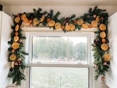 oranges and pine cones are hanging on the window sill in front of a christmas wreath