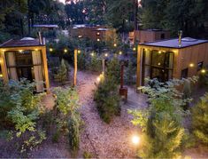 an aerial view of some cabins in the woods with lights on them and trees around