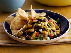 a bowl filled with corn, black beans and tortilla chips on top of a table