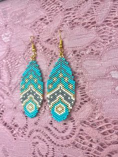 two pairs of beaded earrings sitting on top of a lace doily covered table