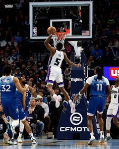 a basketball player dunks the ball in front of his team mates during a game