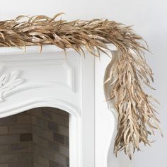 a white fireplace with some dry grass on top