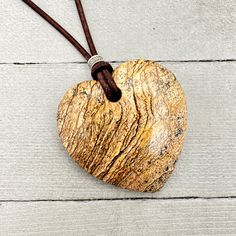 Beautiful Picture Jasper pendant on a rustic brown leather cord. The Picture jasper stone is in the shape of a heart and has gorgeous colors of brown and tan.  Accented with a stamped silver bead and a rustic brown leather cord. The necklace is finished with a Tiger Eye bead and loop closure. Necklace length: 32 inches (58cm) Pendant Size: 48 x 50mm (2 x 2 inches) The necklace is ready for shipping and will be shipped within 24-72 hours from purchase. The necklace will arrive in a gift box with Rustic Brown Jewelry With Adjustable Cord, Rustic Brown Waxed Cord Necklace, Rustic Brown Necklaces With Natural Stones, Brown Waxed Cord Necklace For Gift, Adjustable Brown Jewelry With Heart Charm, Earthy Brown Waxed Cord Necklaces, Earthy Brown Waxed Cord Necklace, Artisan Brown Necklace With Waxed Cord, Artisan Brown Jewelry With Waxed Cord