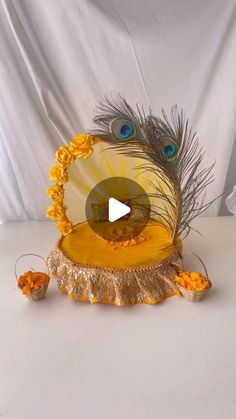 a peacock sitting on top of a table with yellow flowers and feathers in front of it