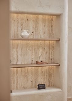 three shelves with shoes and vases on them in a room that has marble walls