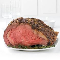 a piece of meat sitting on top of a white plate next to a glass of water