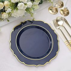 a blue plate sitting on top of a white table next to silverware and flowers