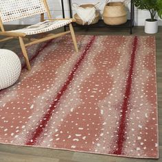 a red rug with white dots on it in a room next to a chair and potted plant