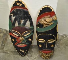 two african masks sitting next to each other in front of a white wall and door