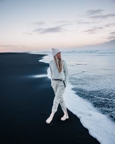 a woman standing on top of a beach next to the ocean