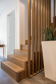 there is a plant on the stairs in this house with wooden handrails and wood flooring