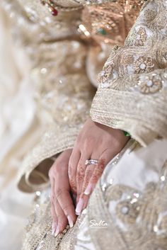 a close up of a person's hands with wedding rings on their fingers and dress