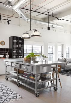 a kitchen island in the middle of a living room with lots of lights hanging from the ceiling