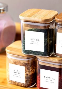 four jars filled with spices sitting on top of a wooden table