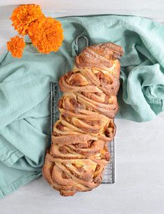 a loaf of cinnamon bread sitting on top of a cooling rack next to an orange flower