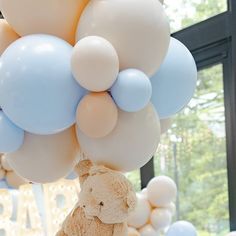 a teddy bear hanging from a bunch of balloons