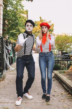 two people in costumes walking down a sidewalk