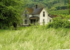 an old house sitting in the middle of some tall grass