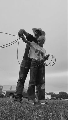 black and white photograph of two people in a field with a rope attached to the ground