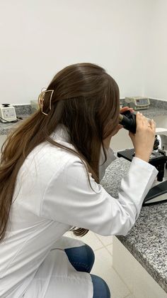 a woman sitting at a counter looking through a pair of binoculars