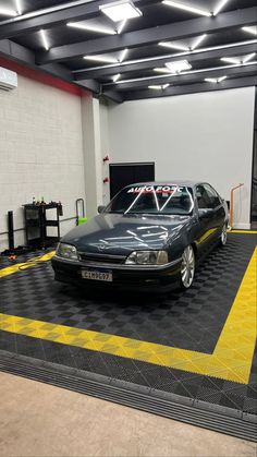 a car is parked in a garage with yellow and black checkered flooring on the ground