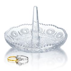 two wedding rings are sitting in front of a glass ashtray with an ornate design on it