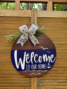 a welcome sign hanging from the side of a wooden fence with a bow on it