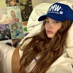 a woman laying in bed wearing a blue hat with wmf on it's brim