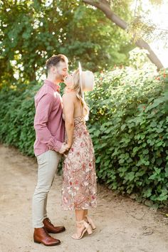 an engaged couple standing in front of some bushes