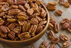 a wooden bowl filled with pecans on top of a table