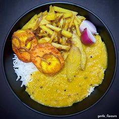 a black plate topped with food and rice