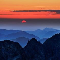 the sun is setting over some mountains in the distance, as seen from high up